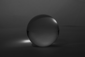 Crystal glass ball sphere transparent on dark grey gradient background.