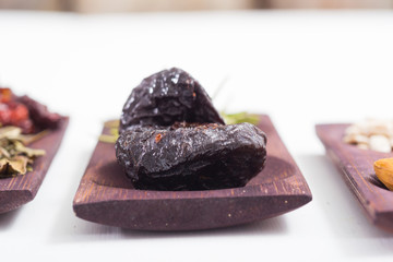 dried fruits and spices on wooden tray, white table