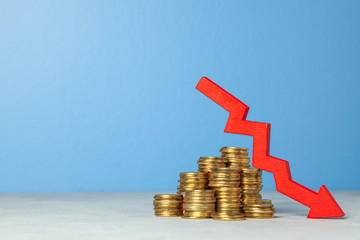 Down arrow and stack of coins. The concept of tax cuts or falling profits in business. Copy space...