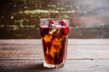 Refreshing cold cherry cola on the wooden background. Selective focus.