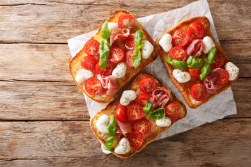 Delicious ciabatta with mozzarella, tomatoes, prosciutto and basil close-up. Horizontal top view