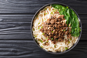 recipe for dan dan noodles with minced meat and greens closeup in a plate. horizontal top view