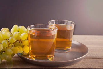 Glass of green grape juice or white wine with bunch of grape on the wooden background.