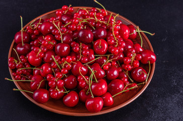 Sweet fresh organic cherry background close-up. Cherry in the plate with leaves on a dark background