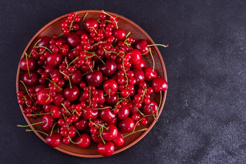 Sweet fresh organic cherry background close-up. Cherry in the plate with leaves on a dark background