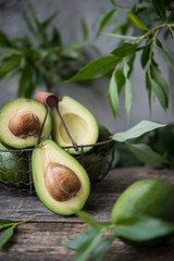 Fresh green avocado with leaves on wooden background. Selective focus.