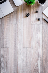 The office desk flat lay view with laptop, mouse, tree, black clip, coffee cup, notebook, pencil on wood texture background.