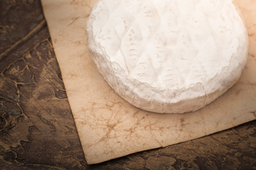 Camembert cheese on old paper. Copy space