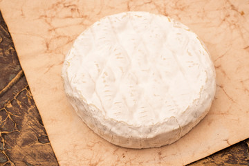 Soft Camembert cheese on old paper. Copy space