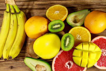 Assortment of tropical fruits on wooden table. Still life with bananas, mango, oranges, avocado, grapefruit and kiwi fruits