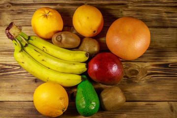 Assortment of tropical fruits on wooden table. Still life with bananas, mango, oranges, avocado, grapefruit and kiwi fruits