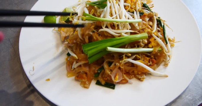 Top Veiw of Pad Thai, Hand Mixing Dish With Chopsticks