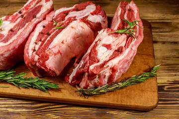 Raw pork ribs with spices and rosemary on wooden table