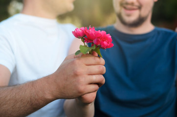 close up of happy male gay couple with red rose flower holding hands. lgbt, homosexuality, same-sex marriage and love concep