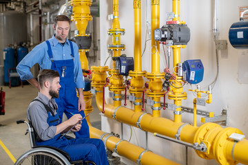 disabled worker in wheelchair in factory and colleague