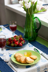 A gourmet breakfast for two: syrnyky, strawberries, grape juice and strawberries.