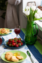 A gourmet breakfast for two: syrnyky, strawberries, grape juice and strawberries.