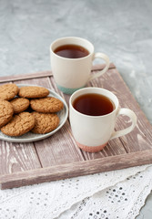 A tasty snack: two cups of tea and a plate of cookies.