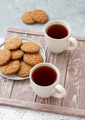 A tasty snack: two cups of tea and a plate of cookies.