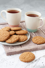 A tasty snack: two cups of tea and a plate of cookies.