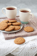 A tasty snack: two cups of tea and a plate of cookies.