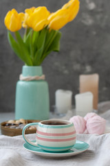 A tasty snack: a cup of coffee, a plate of zephyr and a box of sweets.