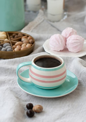 A tasty snack: a cup of coffee, a plate of zephyr and a box of sweets.