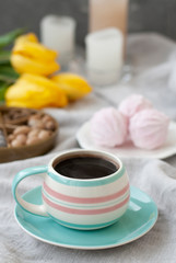 A tasty snack: a cup of coffee, a plate of zephyr and a box of sweets.