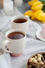 A tasty snack: two cups of tea, a plate of zephyr and a box of sweets.
