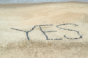 Yes concept word written on sand beach with stones