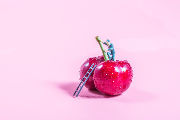 Cherry and little man at work on pink background