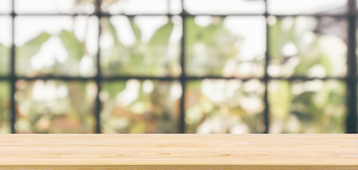 Empty wooden table top with cafe restaurant or coffee shop window interior abstract blur defocused...