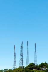 Telecommunication tower antenna and satellite dish on mountain with blue sky background