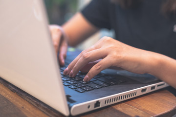 Close up. Business woman black shirts using white laptop hands typing on the notebook keyboard on classic table at cafe. Work space. Programmer concept.