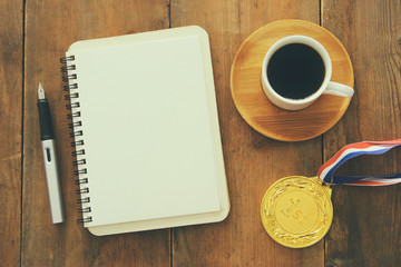 Open notebook with empty pages and other office supplies over wooden old office desk table. Top view, flat lay