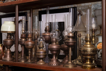 Fototapeta na wymiar Many kind of colorful lamps on wooden shelf, the paraffin lamp or hand-held lanterns used in the past in Vietnam. Ancient collection of old fashioned Kerosene Lamps. High quality free stock image.