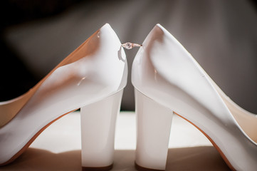 Golden ring with diamond between a pair of white shoes