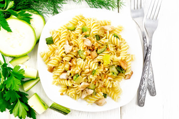 Fusilli with chicken and zucchini in plate on board top