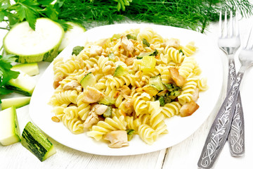 Fusilli with chicken and zucchini in plate on board