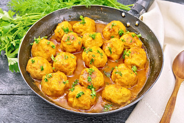 Meatballs in pan with greens on black board