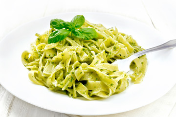 Pasta with pesto sauce in plate on light board