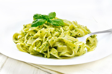 Pasta with pesto sauce in plate on white board