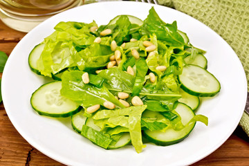 Salad from spinach and cucumber with napkin on wooden board