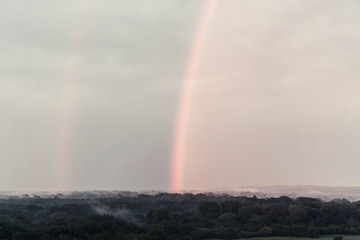 Beautiful double rainbow in sky on sunrise