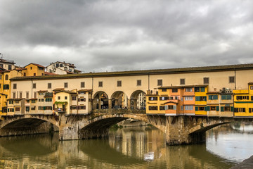 Fototapeta na wymiar Italy, Florence, the capital of Tuscany. View of the famous Ponte Vecchio bridge over the Arno River. Pre-storm May sky.