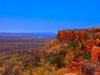Brown desert landscape with rocky mountains and blue cloudless sky stretching to the horizon