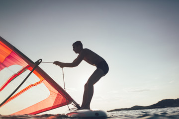 Windsurfer uplift board sail on sunset sea