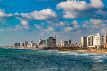 Panoramic view of modern Tel Aviv sky line and beach on sunny day. Mediterranean sea, Israel. Sea waves and cloudy sky.