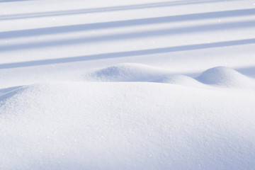 Texture of winter snowdrifts with shadows on a Sunny day, abstract festive background for New year and Christmas