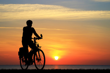 Fototapeta na wymiar Silhouette man and bike relaxing on blurry sunrise sky background.